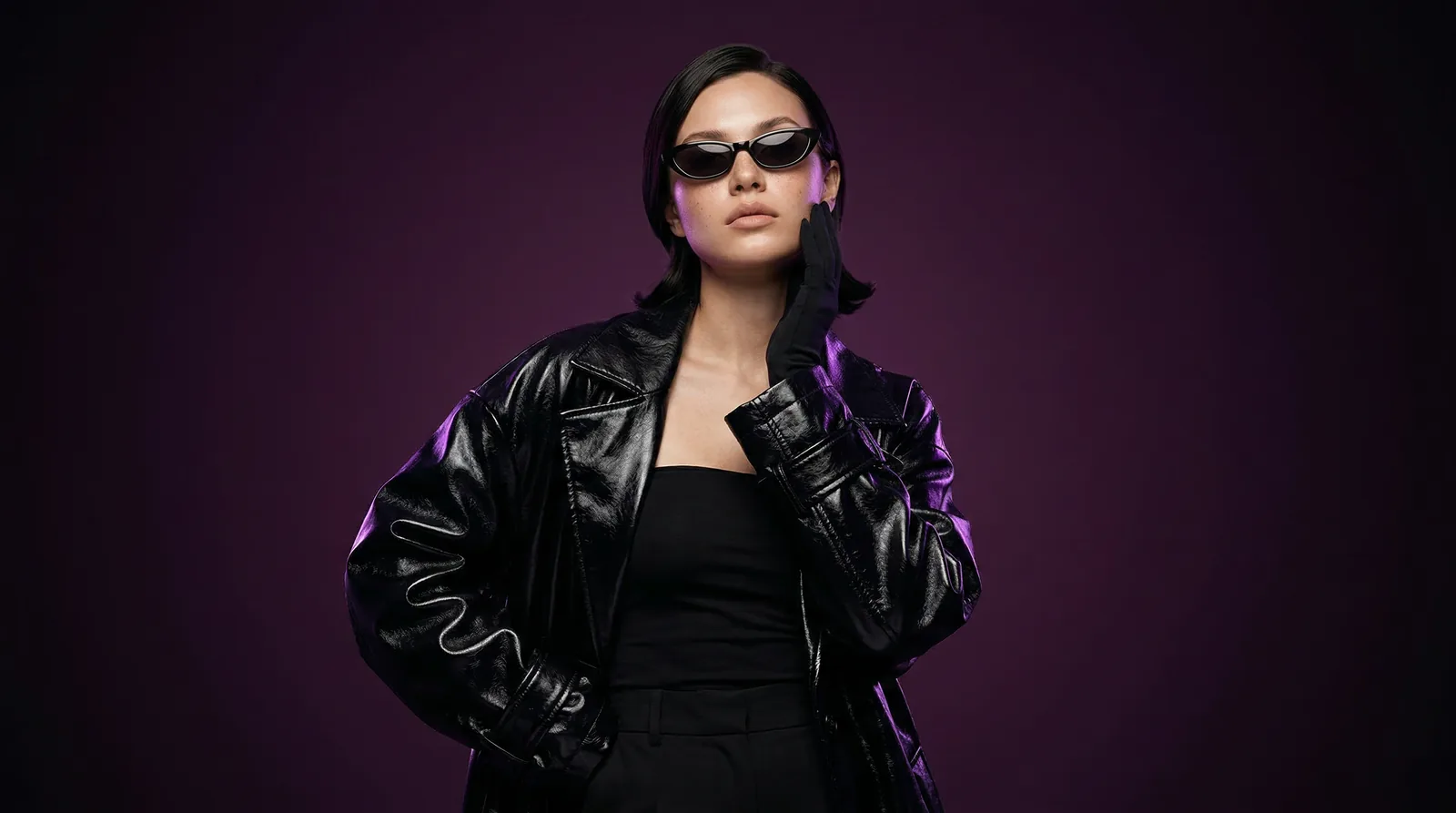 Fotografía editorial de moda generada con IA: modelo con gafas de sol y chaqueta negra sobre fondo morado de estudio